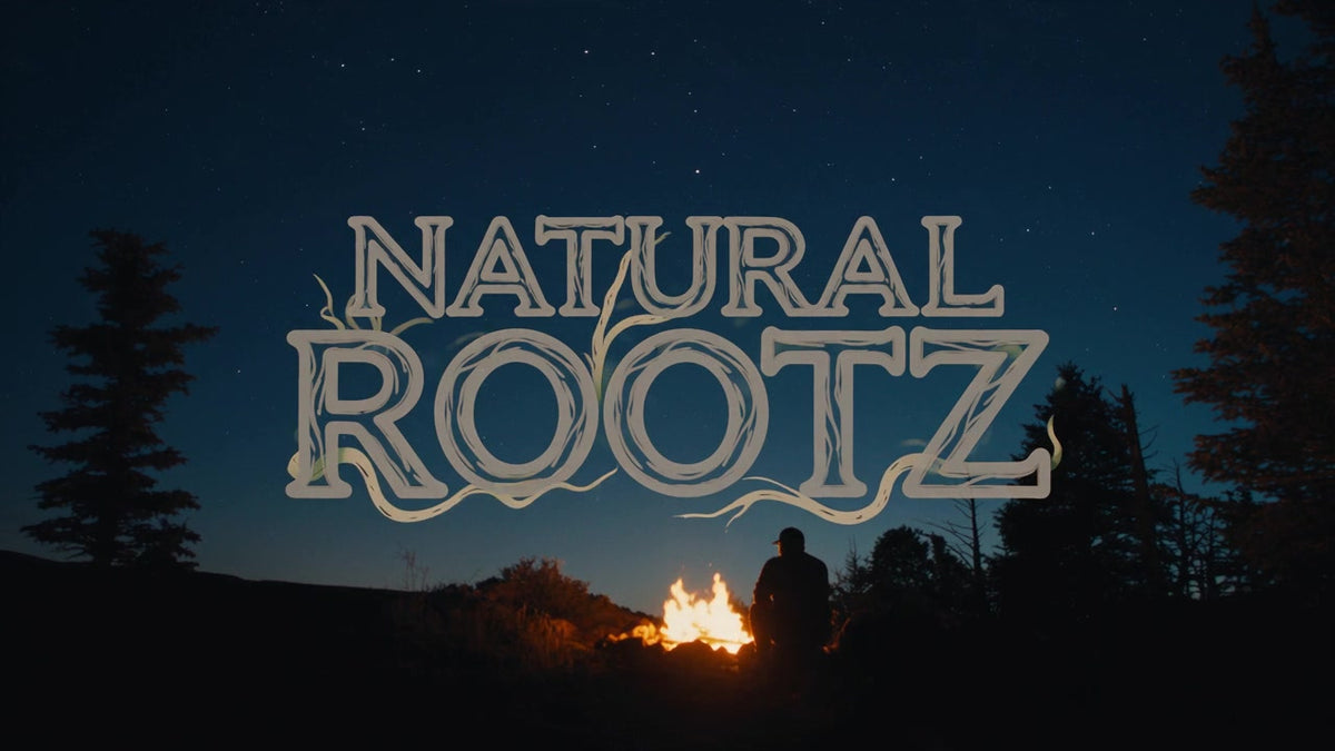 The Natural Rootz mark in the night sky above a campfire